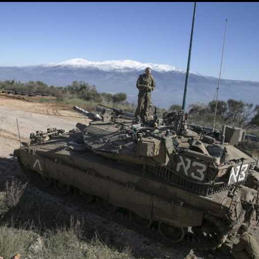 An IDF soldier stands atop a tank near the Lebanese border