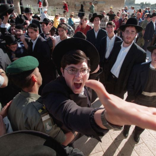 An ultra-orthodox Hassidic Jew is restrained by a Border Policeman as he screams against a group of Reform and Conservative rabbis holding prayers at the Western Wall