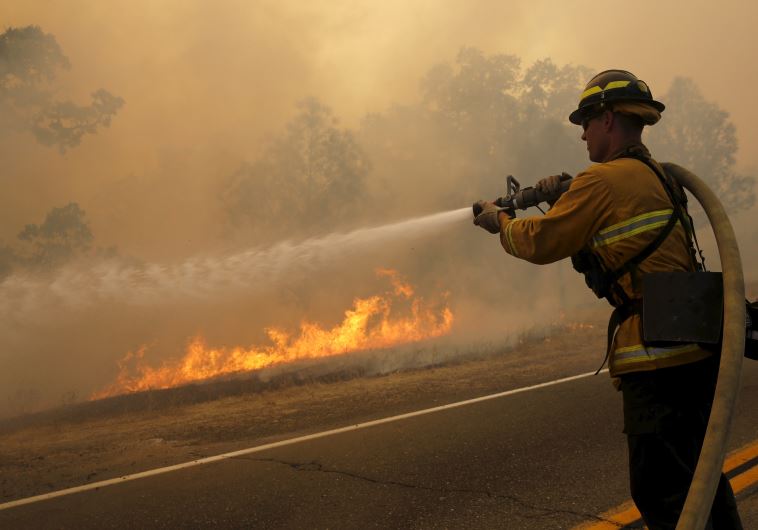 A firefighter uses a hose to extinguish flames.