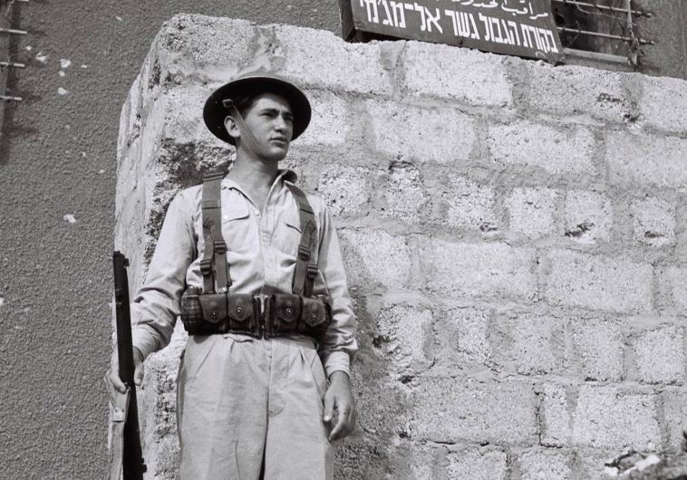 A JEWISH solider stands guard outside a building days after the British Mandate ended in 1948