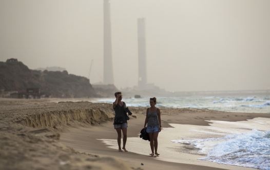 Tourists walk at the shore of the Mediterranean sea in Ashkelon in southern Israel during heavy hazy weather in the region