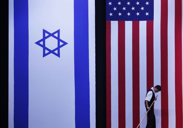 A worker cleans the stage near Israeli and American flags
