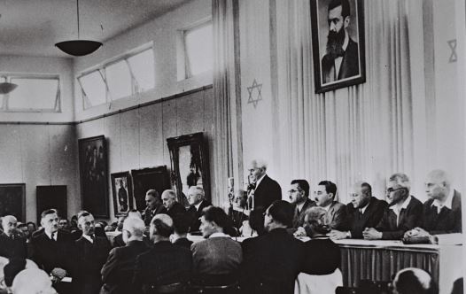 David Ben-Gurion, flanked by the members of his provisional government, reads the Declaration of Independence in the Tel Aviv Museum Hall