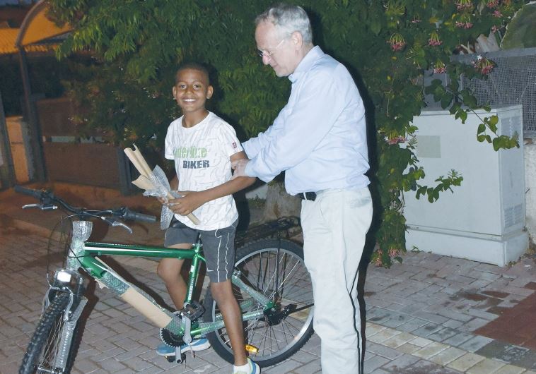 ONEFAMILY founder and chairman Marc Belzberg presents a bicycle yesterday to a son of slain taxi driver Amin Shaaban.