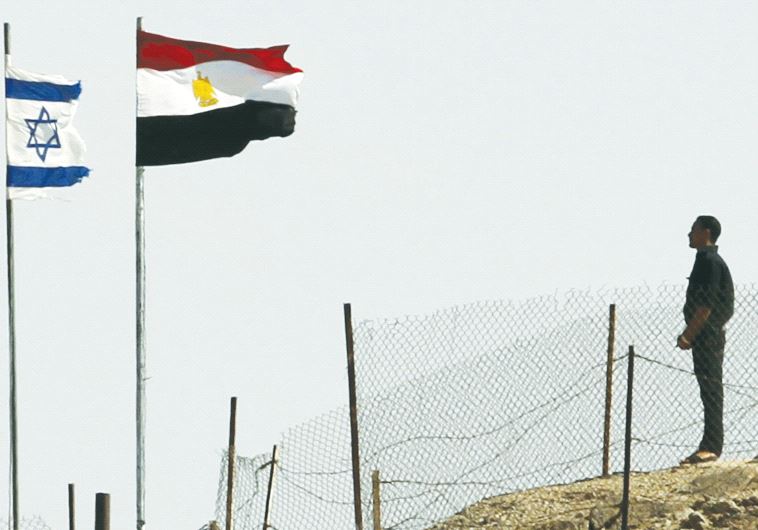 EGYPTIAN AND ISRAELI flags flutter next to each other at the Taba border crossing.