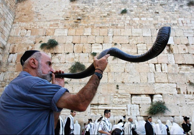 A worshiper blows a shofar at the Western Wall