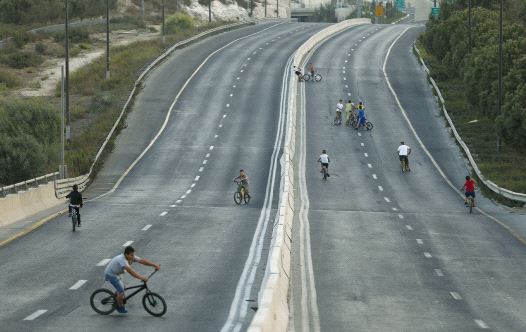 Children ride their bicycles in an empty street in Jerusalem during Yom Kippur