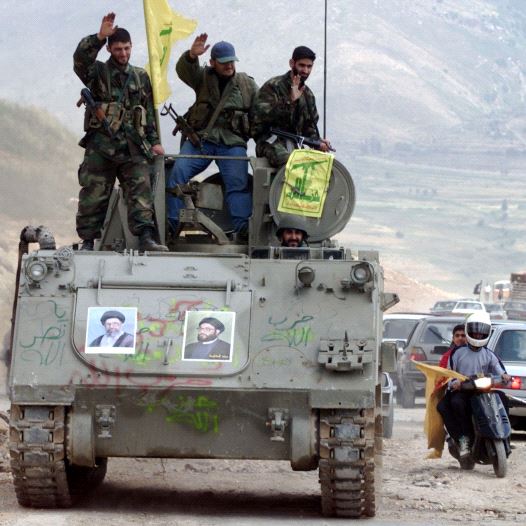 Pro-Iranian Hezbollah guerrillas, riding on an APC M113 used by pro-Israeli militiamen, wave to passing motorists as they drive in the former Israeli security zone in the Tell Nahas area of south Lebanon May 26, 2000.