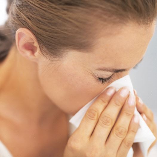A woman blowing her nose into a tissue, possibly after or sneeze or while sick