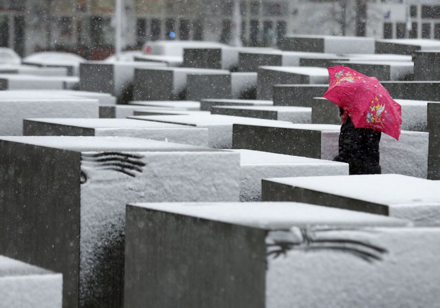 A woman walks through the Holocaust memorial during heavy snowfall in Berlin.