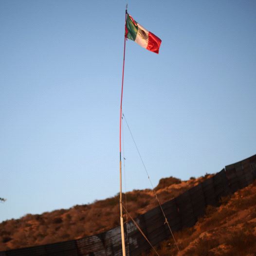 A Mexican flag is seen next to a section of the wall separating Mexico and the United States, in Tijuana, Mexico, October 6, 2016