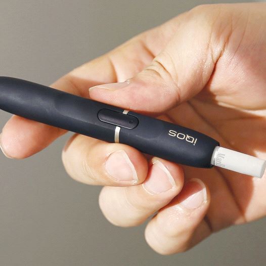 A CUSTOMER holds a Philip Morris iQOS e-cigarette at an iQOS store in Tokyo last year