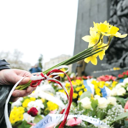 A man lays daffodils near the Ghetto Heroes monument in Warsaw