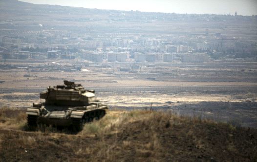 The Syrian area of Quneitra is seen in the background as an out-of-commission Israeli tank parks on a hill, near the ceasefire line between Israel and Syria, in the Golan Heights.