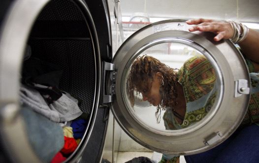 A woman loads laundry into the washing machine at a laundromat in Cambridge, Massachusetts July 8, 2009.