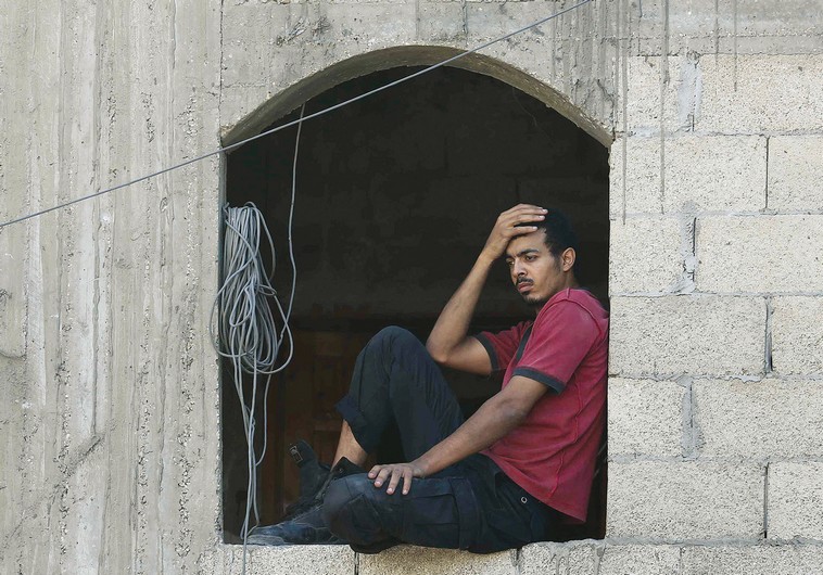A palestinian man reacts as he looks at a neighboring house which police said was destroyed in air strikes by the IDF in Khan Yunis in the southern Gaza Strip on Tuesday.