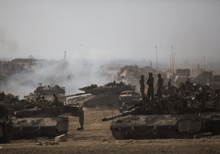 Israeli soldiers stand atop a tank at a staging area, near the border with the Gaza Strip