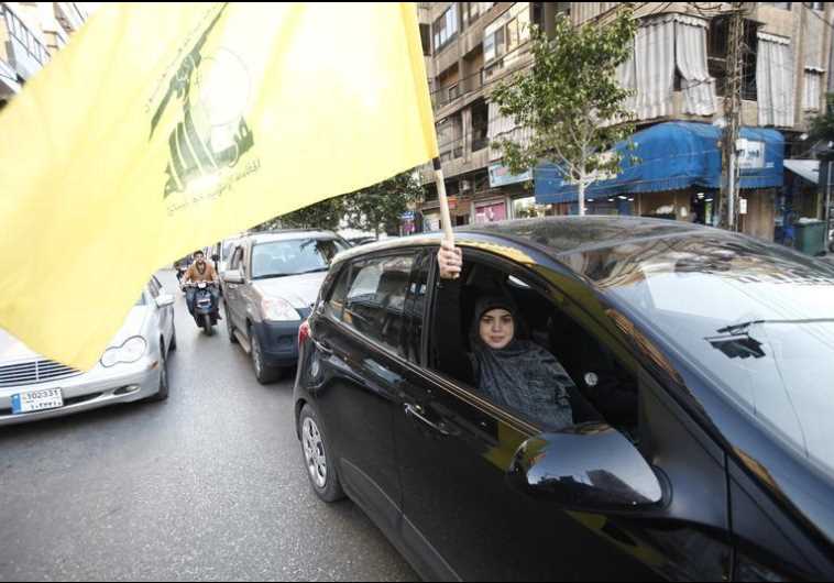 A Hezbollah supporter waves a flag in Beirut's southern suburbs