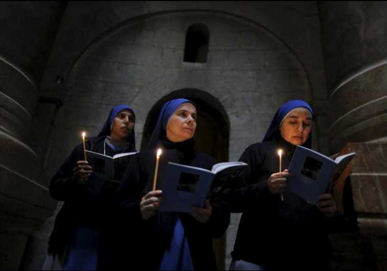Catholic nuns hold candles as they take part in the Washing of the Feet ceremony in the Church of the Holy Sepulchre in Jerusalem's Old City