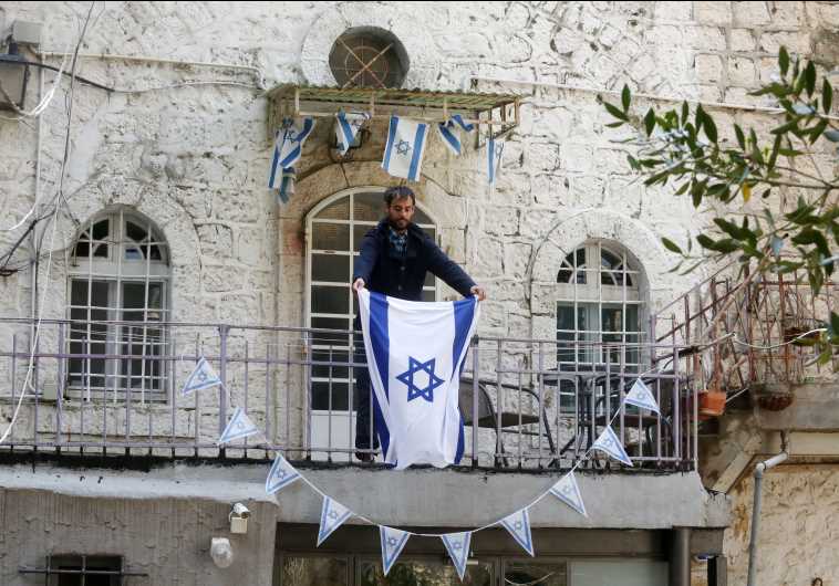 YONATAN SINDEL places an Israeli flag on his balcony