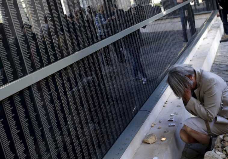 A woman prays in front of a wall bearing the names of victims during Holocaust Memorial day at Budapest's Holocaust Memorial Center