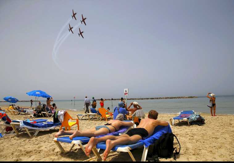 Beachgoers watch the Israeli Air Force Aerobatic team rehearse over the Mediterranean Sea in preparation for an aerial display on Israel's Independence Day in Tel Aviv April 20, 2015.