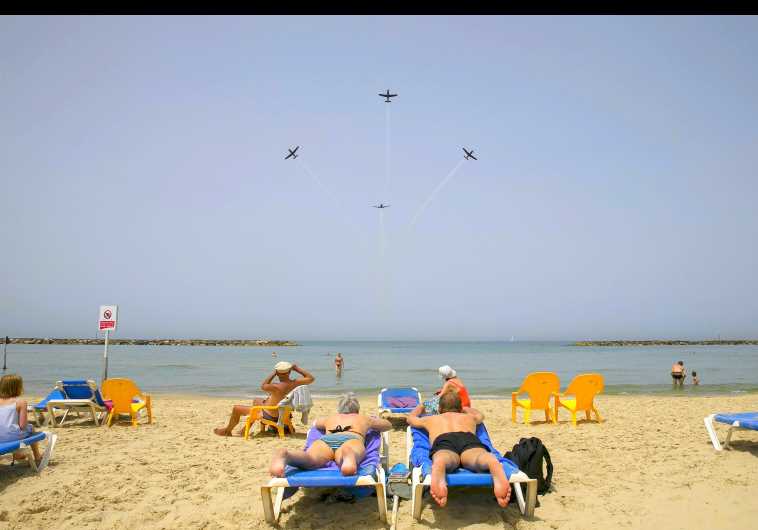 Beachgoers watch the Israeli Air Force Aerobatic team rehearse over the Mediterranean Sea in preparation for an aerial display on Israel's Independence Day in Tel Aviv April 20, 2015.