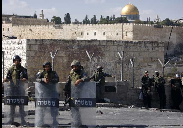 The Dome of the Rock is seen in the background as Israeli border police officers stand guard