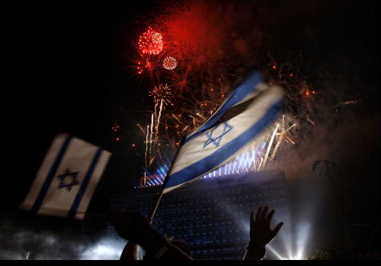 Israelis wave national flags as they watch fireworks during celebrations marking Israel's Independence Day in Tel Aviv 