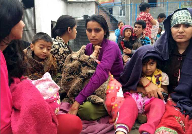People wait at a school after a 7.7 magnitude earthquake struck, in Kathmandu, Nepal, April 25, 2015.