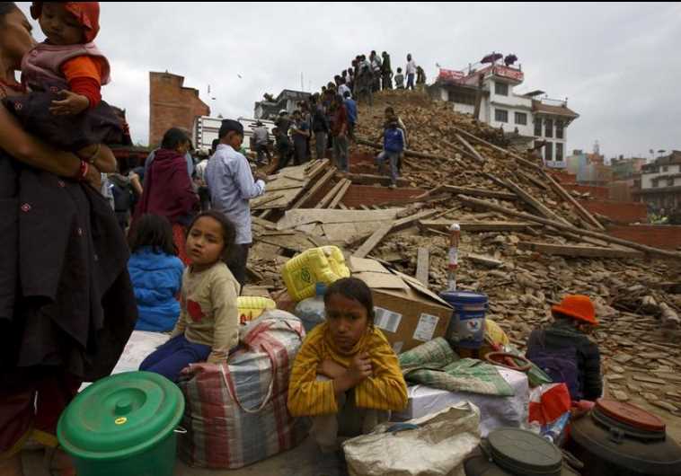 People sit with their belongings outside a damaged temple in Bashantapur Durbar Square after a major earthquake hit Kathmandu, Nepal April 25, 2015.