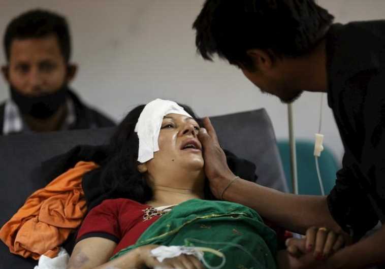 A boy comforts his mother who was injured during an earthquake, at a trauma center in Kathmandu