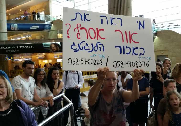 At Ben-Gurion Airport, Orit Asraf holds up a sign asking for information on her son who is missing in Nepal