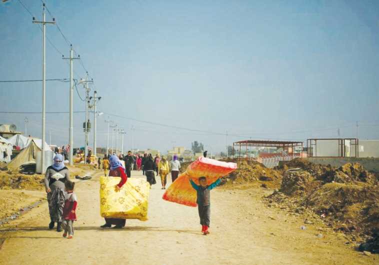 Refugees in Dohuk, Iraqi Kurdistan, carry mattresses provided by IsraAid.