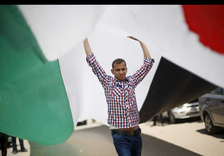 A demonstrator in Gaza City holds a Palestinian flag during a rally calling on rivals Hamas and Fatah to end their political division