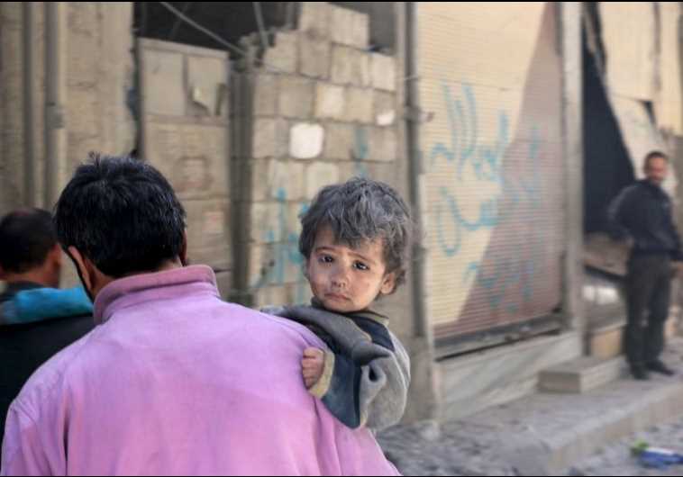 A man carries a child who survived after he was pulled from under rubble following what activists said was shelling by forces loyal to Syria's President Bashar Assad in a suburb of Damascus