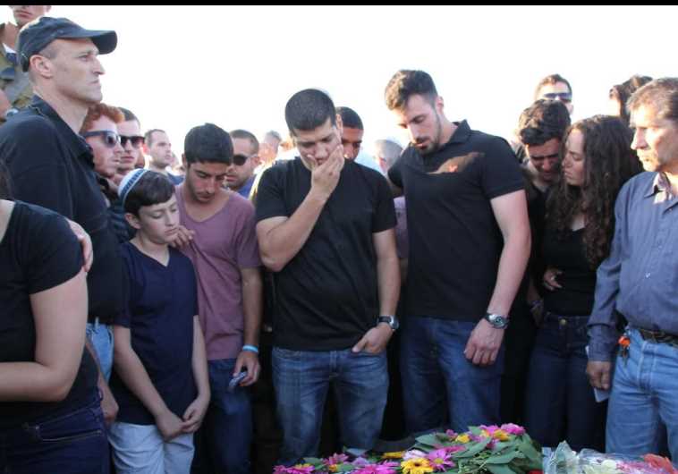 PATRICK ASRAF (second left) watches as a mourner lays a wreath on the grave of his son, Or, at Lehavim, May 6, 2015.