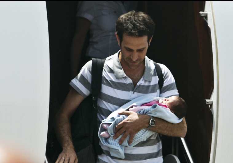 An Israeli man holds his baby, born to a surrogate mother, after being evacuated from Nepal and landing at Sde Dov Airport in Tel Aviv on April 27.