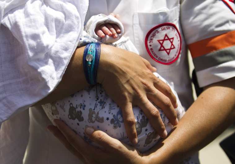 A MDA medic holds a baby, born to a Napalese surrogate mother [Illustrative]