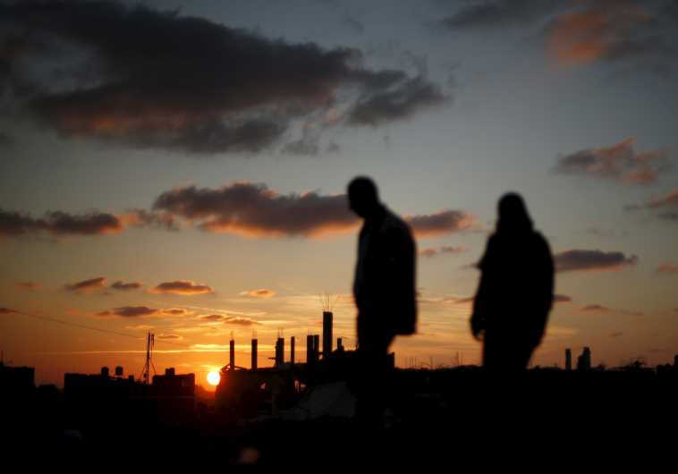 Palestinians walk past houses that witnesses said were destroyed during Operation Protective Edge last summer