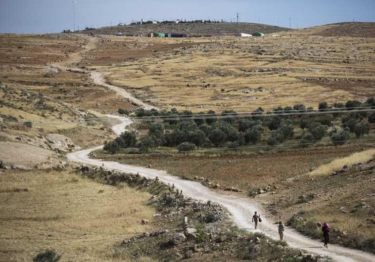 Palestinians walk on a dirt road near the West Bank Jewish settlement of Maon, south of Hebron May 19, 2014