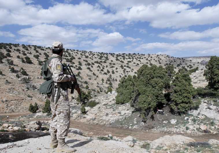 A Lebanon Hezbollah fighter carries his weapon as he stands in Khashaat, in the Qalamoun region