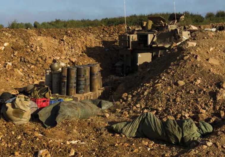 A soldier sleeps in a trench next to an armored vehicle on the Golan Heights.