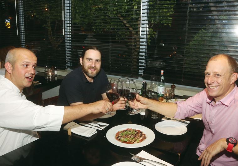 Designer Yaron Loubaton (right) raises his glass with chef Moti Ahana (left) and interviewer Asaf Finkelstein.