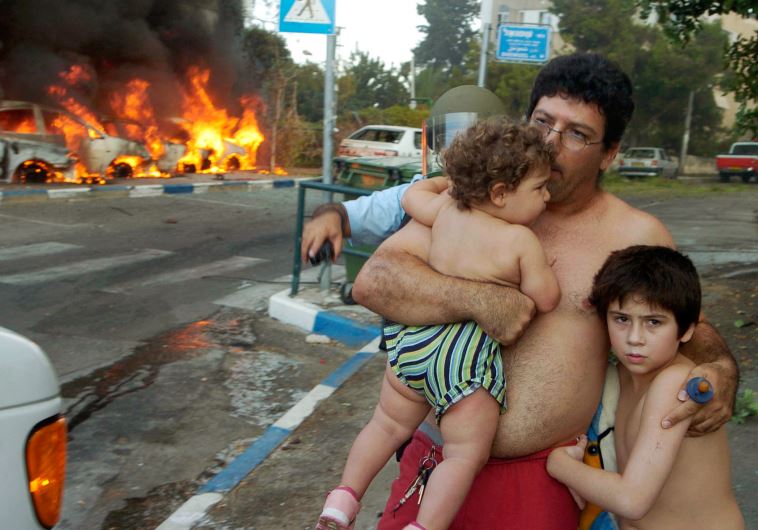 An Israeli man stands with his children at the scene of a rocket attack in Haifa, August 13, 2006