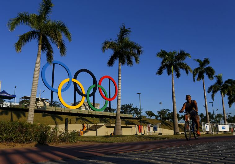 A man exercises next to the Olympic rings placed at the Madureira Park ahead the Rio 2016 Olympic Games