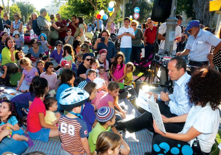 Jerusalem Mayor Nir Barkat helps kick off the opening by reading to a group of children in the park.