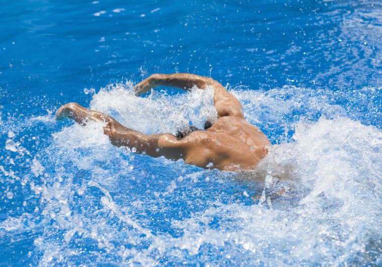 Rear view of a man swimming the butterfly stroke in a swimming pool (illustrative).