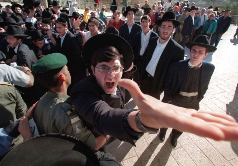 An ultra-orthodox Hassidic Jew is restrained by a Border Policeman as he screams against a group of Reform and Conservative rabbis holding prayers at the Western Wall