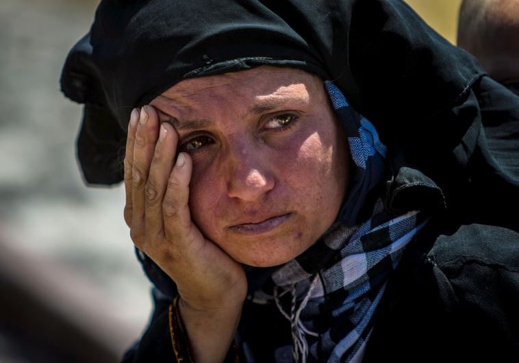 A woman reacts as she rests from walking back to Tel Abyad town, Raqqa governorate, after fleeing Maskana town in the Aleppo countryside